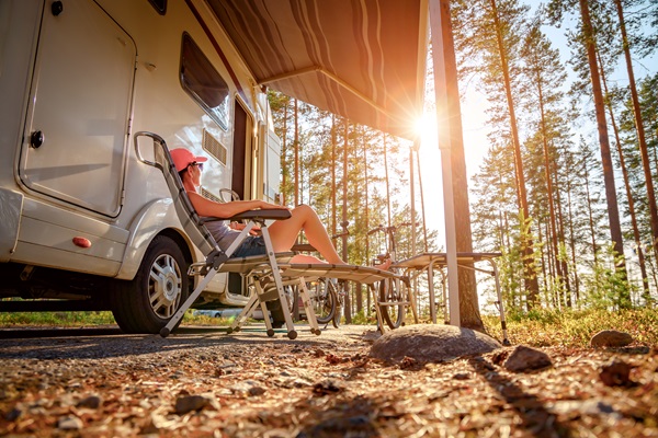 vrouw zit voor de camper te genieten van de natuur