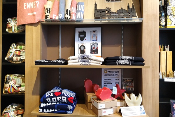 Ein Holzregal mit T-Shirts, Kerzen, Souvenirs und regionalen Produkten.